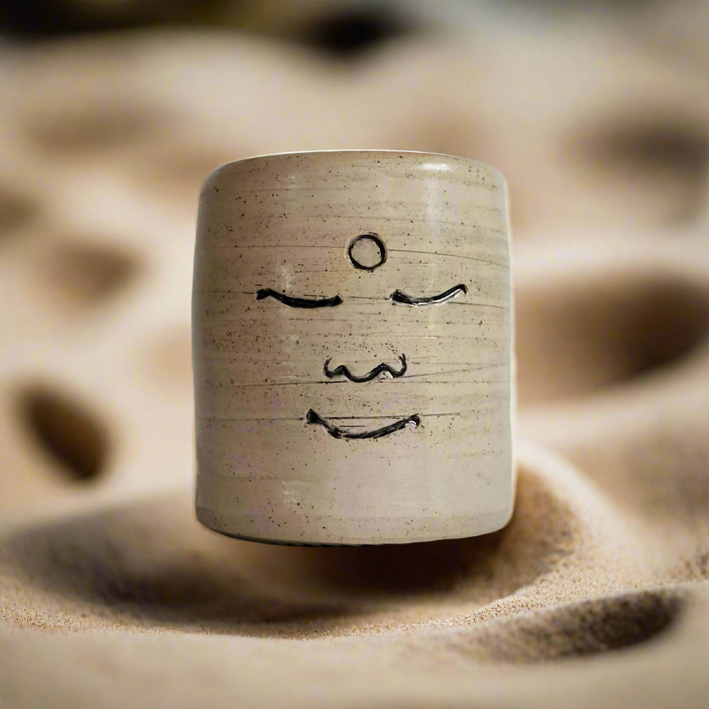 Ceramic mug with a face drawing on a plain background
