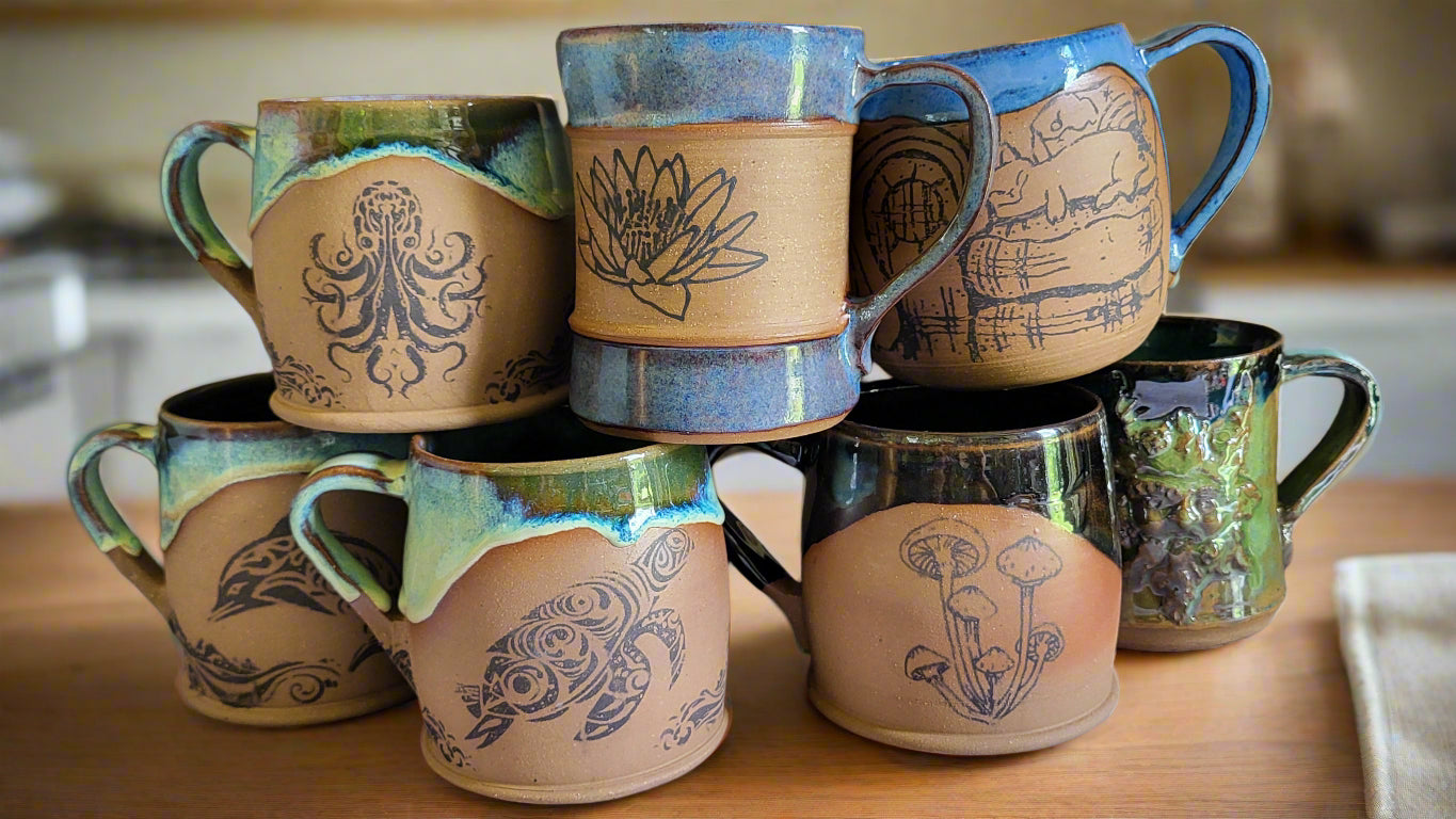 Collection of ceramic mugs with various designs on a white surface.