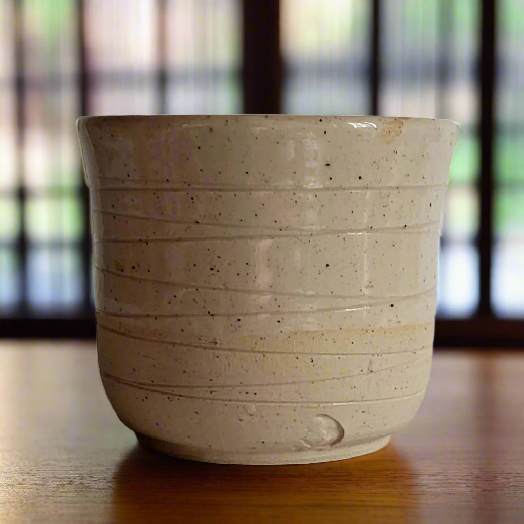 Beige ceramic cup with textured surface on a plain background
