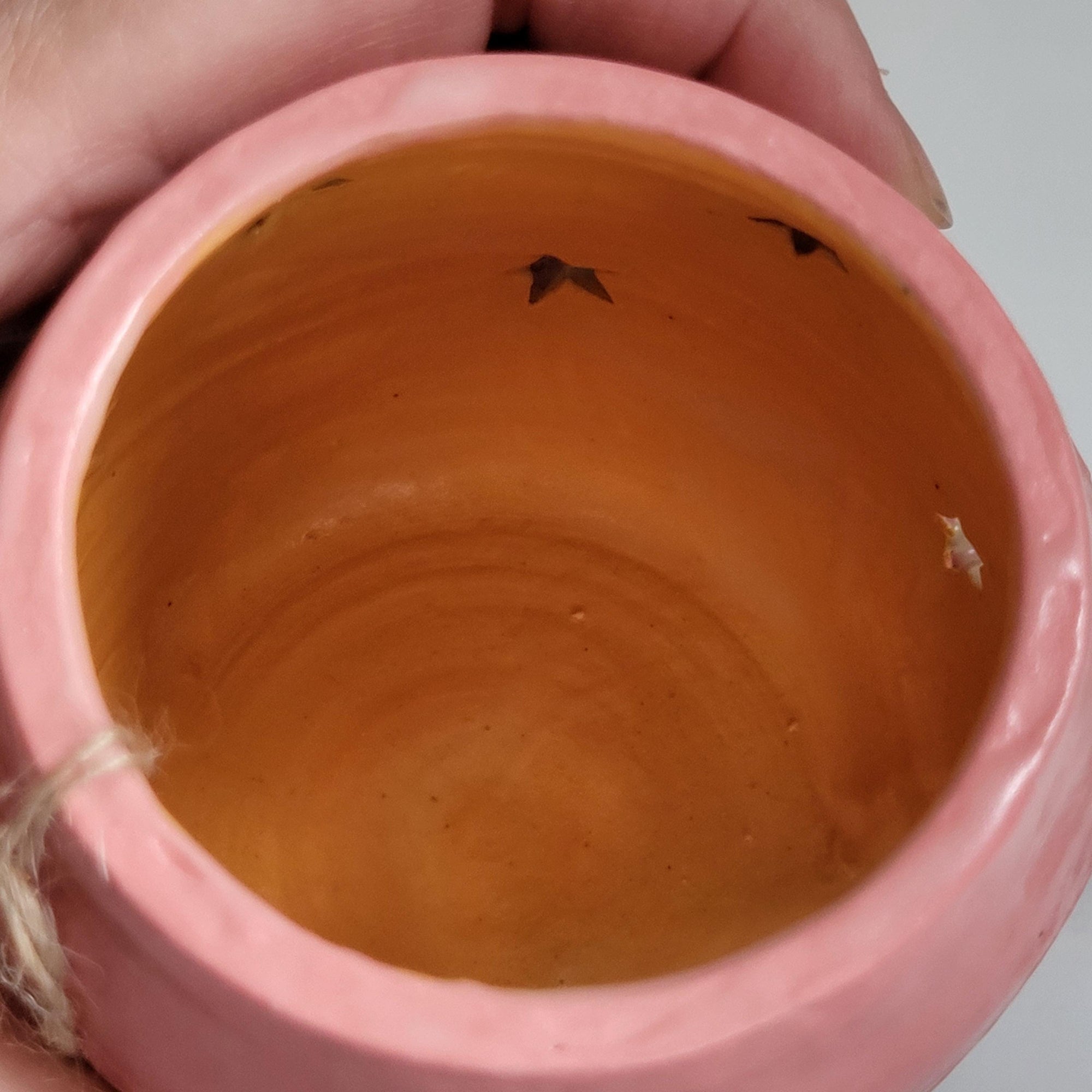 Tea light candle holder with star cutouts and pink and aqua glaze