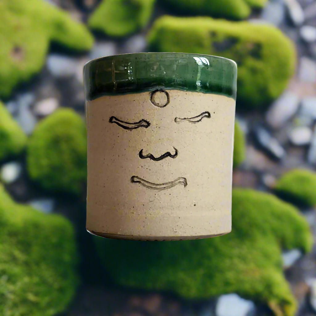 Ceramic tea cup with green glaze on a plain background