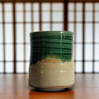 Ceramic mug with green and beige glaze on a white background