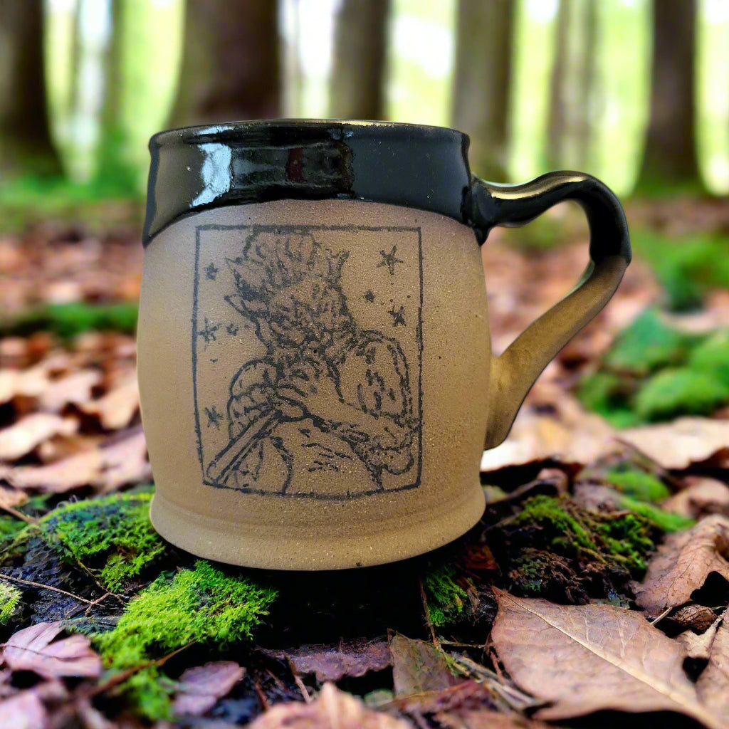 Ceramic mug with a black handle and a decorative design on a neutral background