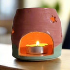 Ceramic candle holder with a lit tealight candle on a neutral background