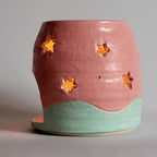 Tea light candle holder with star cutouts and pink and aqua glaze