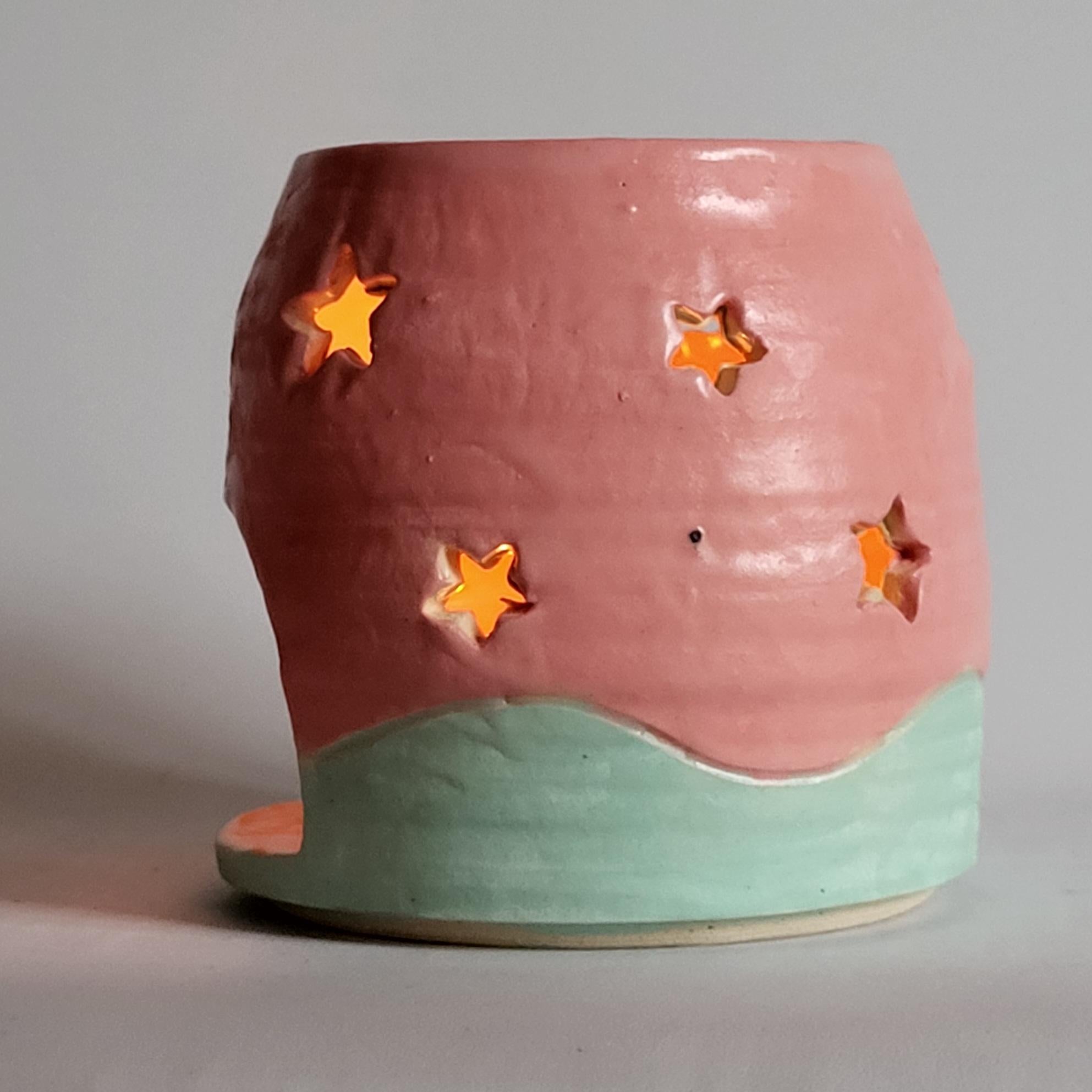 Tea light candle holder with star cutouts and pink and aqua glaze